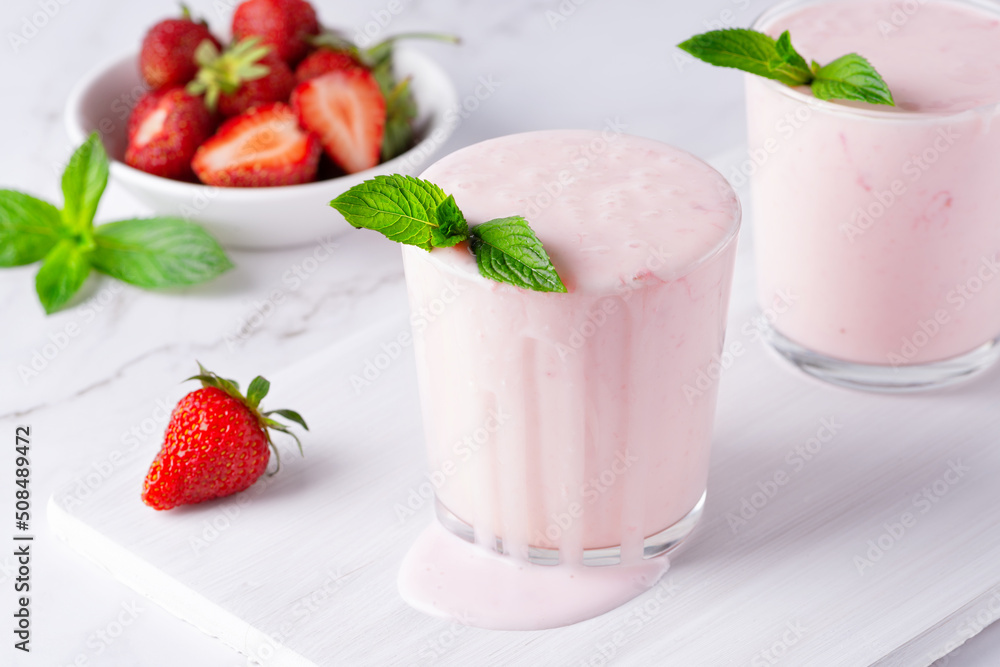 Yogurt , buttermilk or kefir with strawberry. Yogurt in glass on light background. Probiotic cold fermented dairy drink. Gut health, fermented products, healthy gut flora concept Yogurt , buttermilk or kefir with strawberry. Yogurt in glass on light background. Probiotic cold fermented dairy drink. Gut health, fermented products, healthy gut flora concept