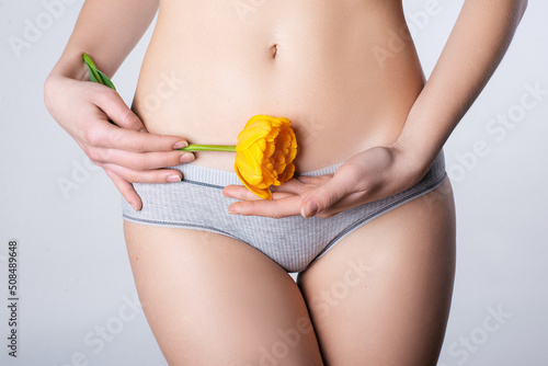 bloom yellow flower in hands. girl in sexy lingerie on a light background. concept gynecology health intimate hygiene photo