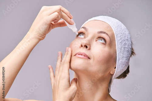 Young woman doing morning routine. Home maternity treatment. Health care concept. Female person. Eyedrop glaucoma concept. Eyewash treatment. White drop photo