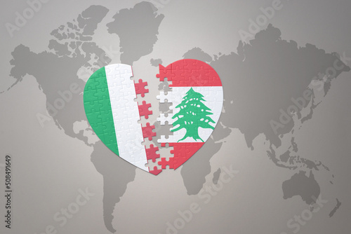 puzzle heart with the national flag of lebanon and italy on a world map background. Concept. photo