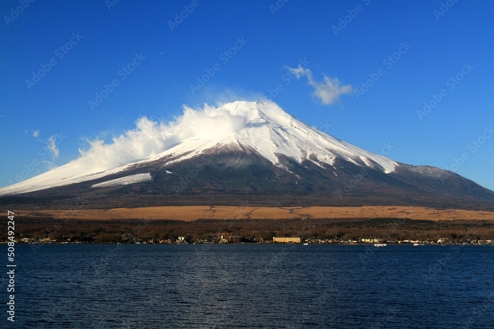 Fuji mountain with snow and fog covered top, lake or sea and clear blue sky background with copy space. This place famous in Japan and Asia for people travel to visit and take picture. Fuji mountain with snow and fog covered top, lake or sea and clear blue sky background with copy space. This place famous in Japan and Asia for people travel to visit and take picture.