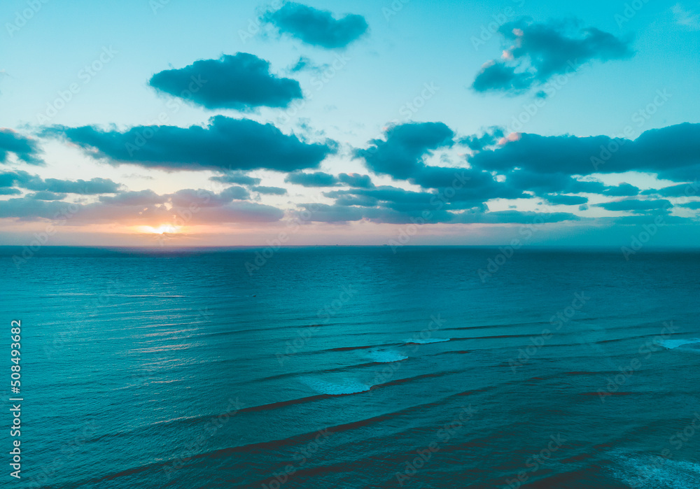 Aerial drone shot of sunrise with cloudy sky and flat Caribbean Sea in Tulum 