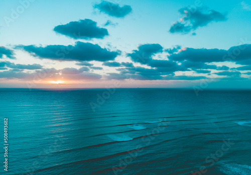 Aerial drone shot of sunrise with cloudy sky and flat Caribbean Sea in Tulum  © Cualera