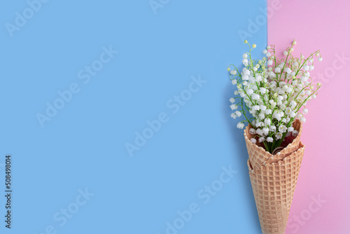 Fototapeta Naklejka Na Ścianę i Meble -  Bouquet of lilies of the valley on blue and pink background. Flat lay, top view, copy space. floral background with spring flowers.  Mother's day, Valentines Day, Birthday celebration concept