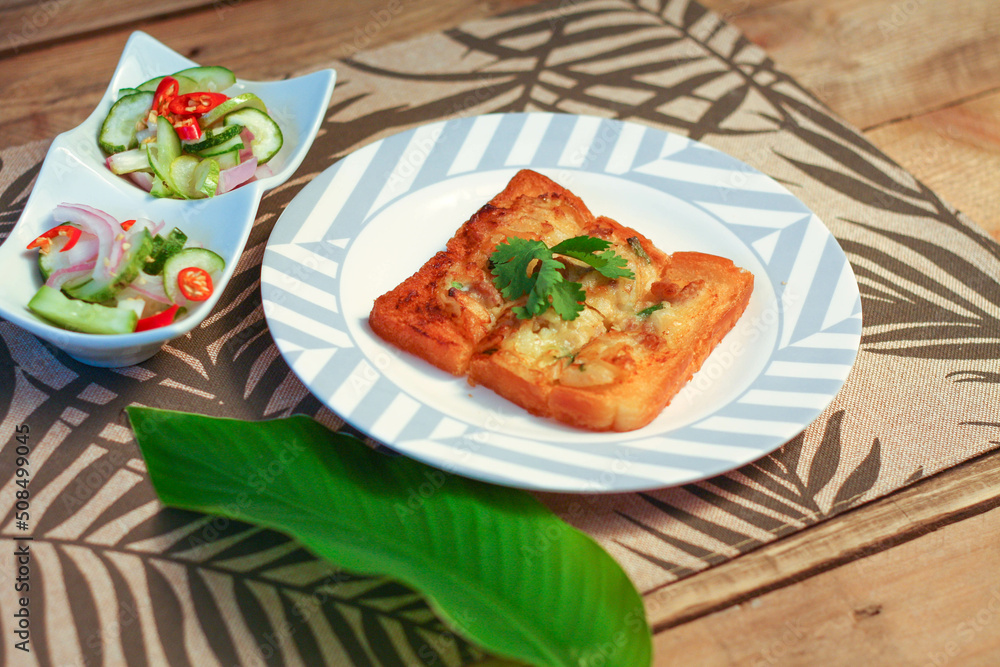 Fried bread with minced pork spread with cucumber dipping sauce on a wooden table. Fried bread with minced pork spread with cucumber dipping sauce on a wooden table.