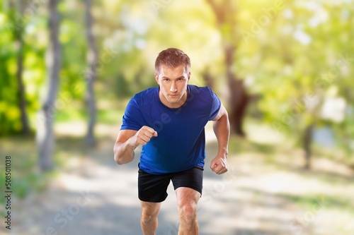 Young strong fitness man running in park