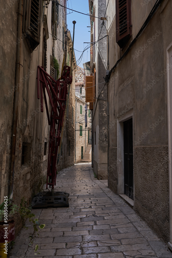 Fototapeta premium Sibenik, Croatia - May 26, 2022 - narrow old street and yard in Sibenik city, medieval zone
