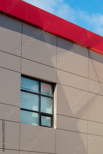 The exterior wall of a contemporary commercial style building with aluminum metal composite panels and metal columns. The futuristic building has engineered diagonal cladding steel frame panels.