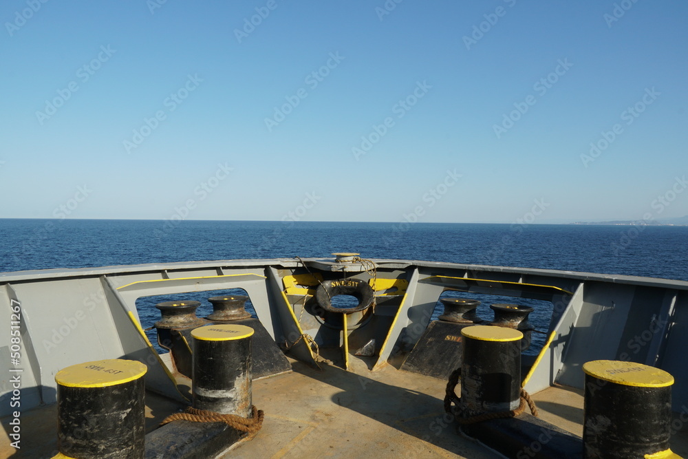 View on the Mediterranean Sea from forward mooring station on bow of the cargo container ship. On picture are bollards and mooring rollers and Panama bow. In horizon are film of mist below blue sky.