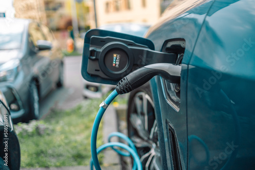 Power supply for electric car charging. Electric car charging station on urban europe street with blurred nature background.