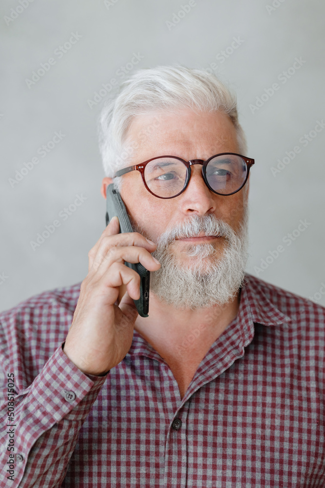 man with gray hair is working in an office on a laptop and talking on the phone. an adult male director or businessman is negotiating on an online webcam. business and finance of a male lawyer or man with gray hair is working in an office on a laptop and talking on the phone. an adult male director or businessman is negotiating on an online webcam. business and finance of a male lawyer or