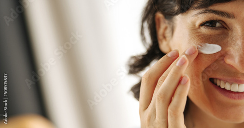 Canvas Print Close-up of joyful young caucasian woman with cosmetic moisturizing face cream