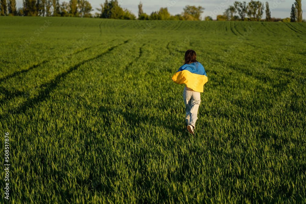 Girl with flag of Ukraine runs across the field close-up and copy space. Girl with flag of Ukraine runs across the field close-up and copy space.