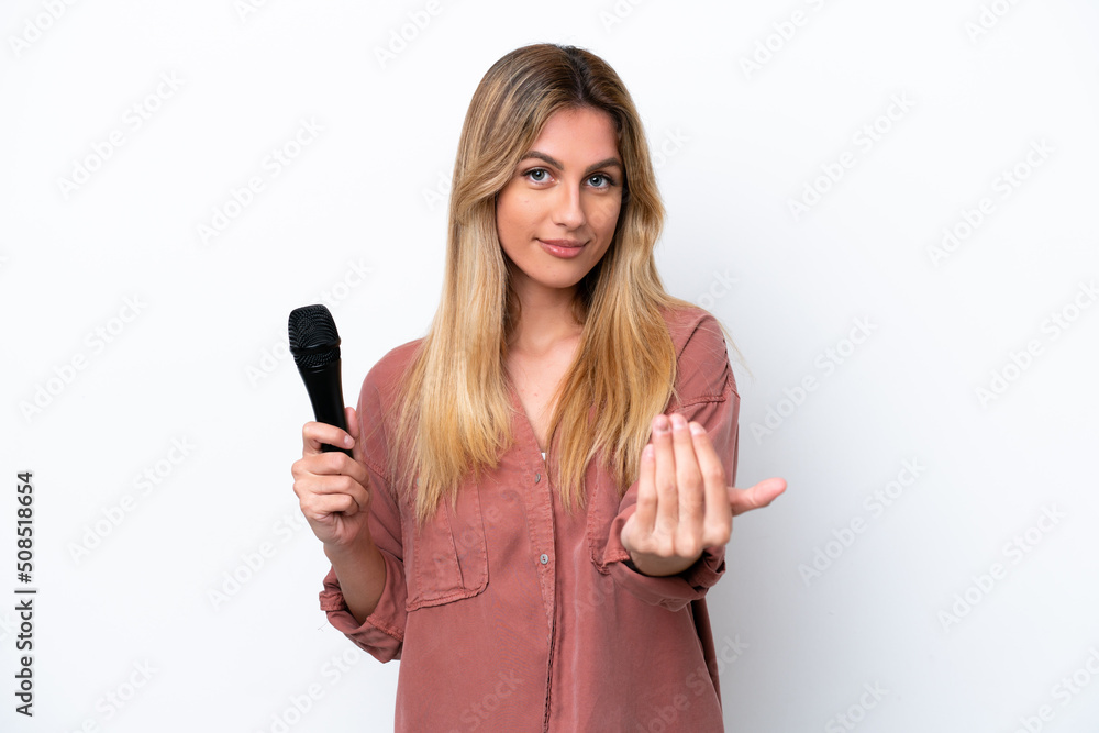 Singer Uruguayan woman picking up a microphone isolated on white background inviting to come with hand. Happy that you came Singer Uruguayan woman picking up a microphone isolated on white background inviting to come with hand. Happy that you came