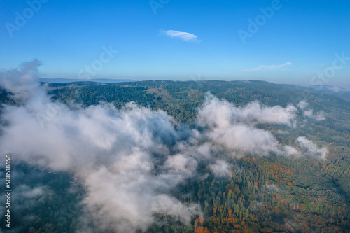 Aerial view of the foggy morning at the green mountains, clear blue sky. 