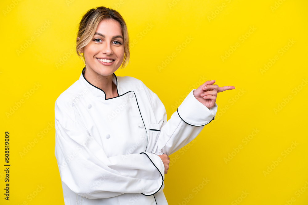 Uruguayan chef woman isolated on yellow background pointing finger to the side Uruguayan chef woman isolated on yellow background pointing finger to the side