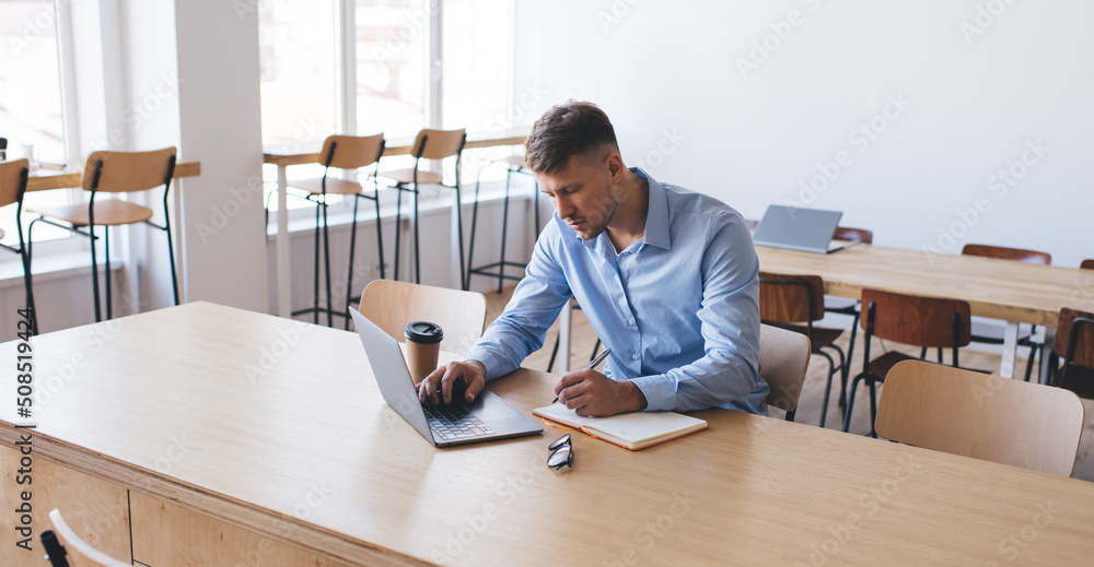 Skilled male copywriter with notepad planning text publications and creating content plan during remote working, young hipster guy with modern laptop computer e learning education information Skilled male copywriter with notepad planning text publications and creating content plan during remote working, young hipster guy with modern laptop computer e learning education information