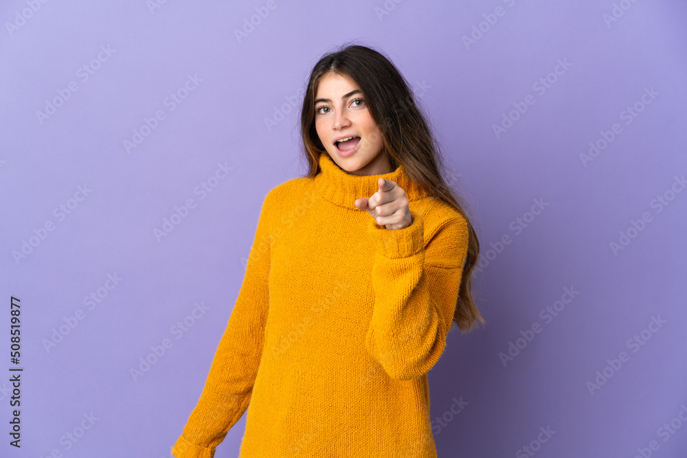 Fototapeta premium Young caucasian woman isolated on purple background surprised and pointing front