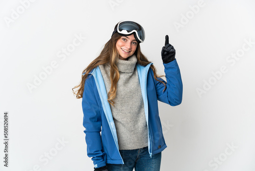 Skier girl with snowboarding glasses isolated on white background pointing up a great idea