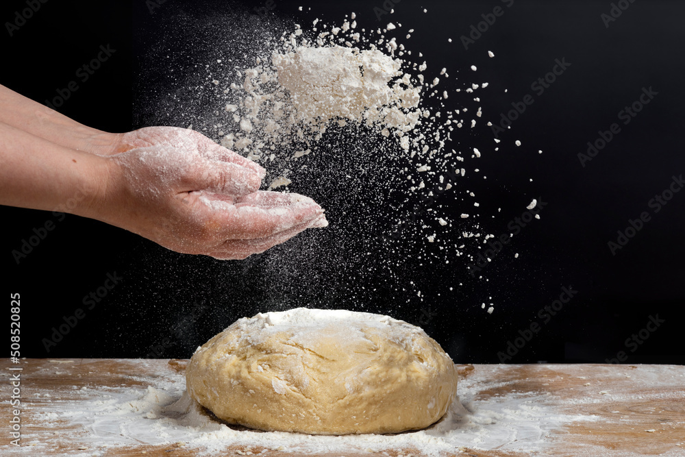 Obraz premium Strong male hands kneading the dough for homemade bread. Baker man kitchener in a black shirt cooking pastry