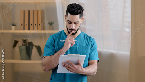 Hispanic physician male doctor man therapist medic wear uniform standing in hospital clinic writing notes fill medical form insurance notice detailed prescription receipt prescribe treatment patient