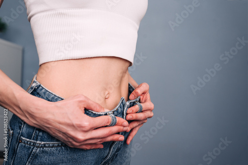 Slim woman in too big jeans showing how she was losing weight when she started eating healthy food photo