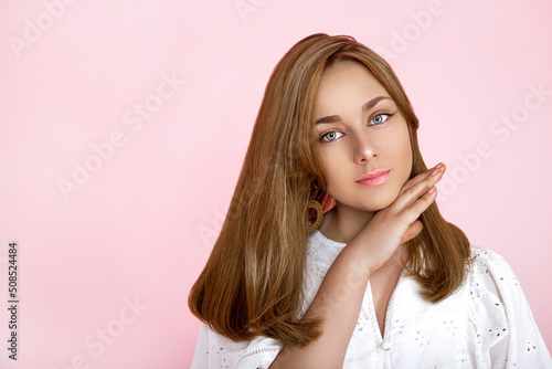 Portrait of a beautiful natural and smiling girl on a pink background. Beautiful young girl with perfect face and beautiful hair is posing in studio. Beauty, makeup, hair. Perfect face.