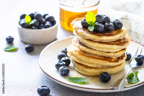 Pancakes stack with fresh blueberries and honey close up.