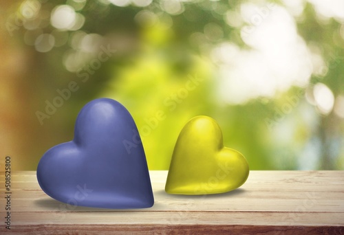 Two hearts on the wooden table and two hearts in colors of Ukrainian flag