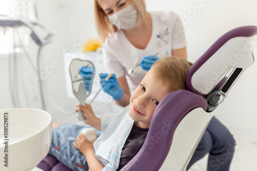 Cute little boy sitting on dental chair and smiling