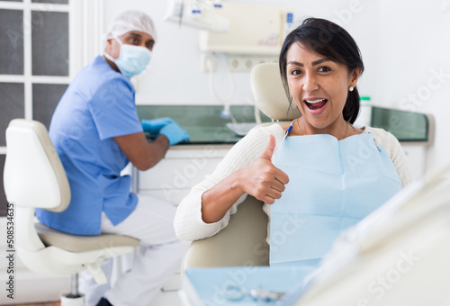 Portrait of satisfied woman visiting dentist giving thumbs up in the dental clinic