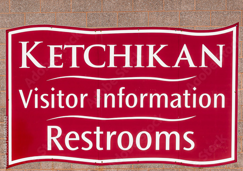 Ketchikan, Alaska, USA - July 17, 2011: Closeup of white on red town sign naming visitor center and restroom, located in port.