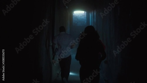 Group of friends with flashlights running through dark tunnels