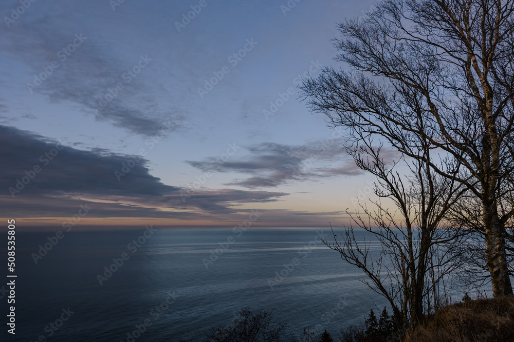Blue sky at sunset with clouds and haze, with warm shades of the setting sun, over the calm Baltic Sea. Blue sky at sunset with clouds and haze, with warm shades of the setting sun, over the calm Baltic Sea.