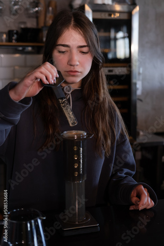 pretty brunette girl making aeropress coffee in modern coffee shop © OliaVesna