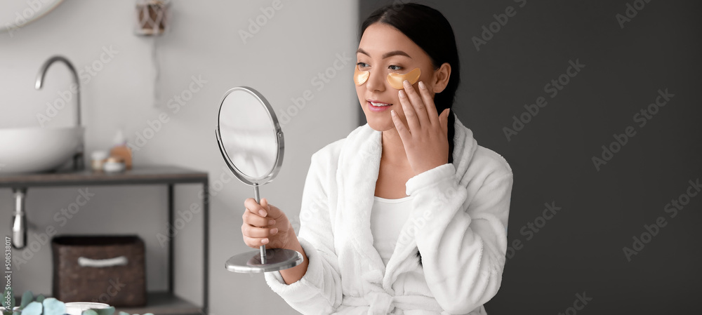 Beautiful Asian woman applying under-eye patches in bathroom Beautiful Asian woman applying under-eye patches in bathroom