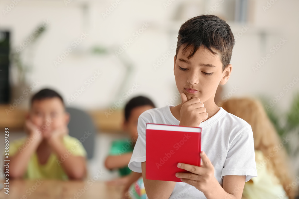 Thoughtful little boy with book in classroom Thoughtful little boy with book in classroom