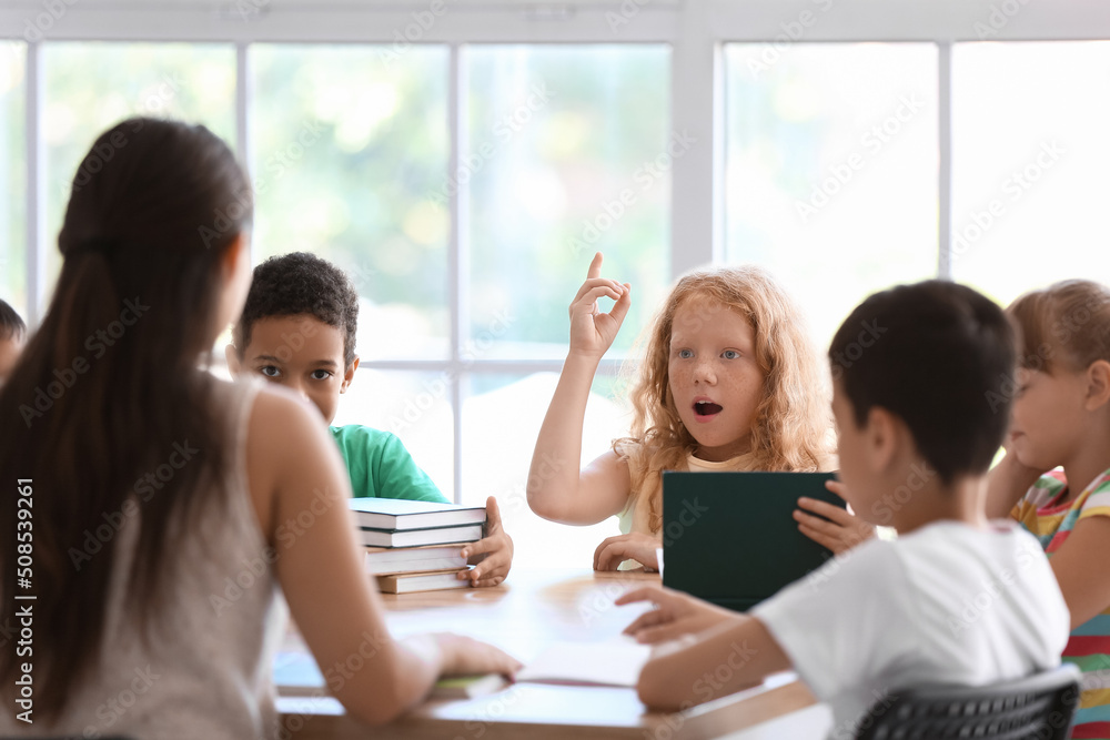 Obraz premium Little redhead girl asking question during literature lesson in classroom