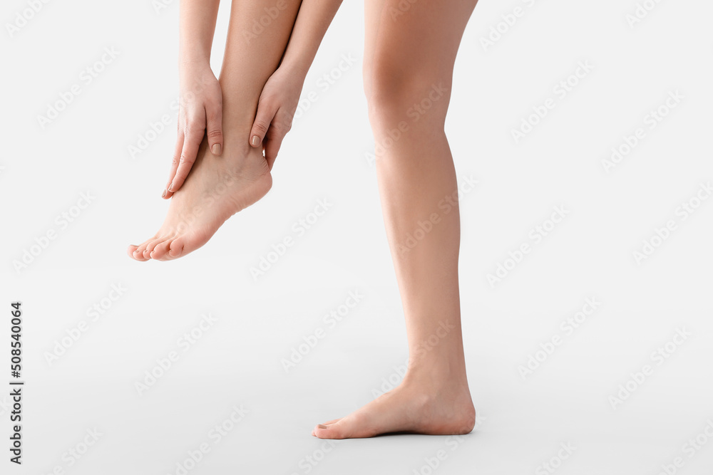Young woman making foot massage on light background, closeup Young woman making foot massage on light background, closeup