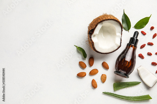 Fotobehang Bottle of natural serum with coconut, plant leaves, goji berries and almond nuts