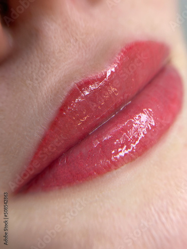 permanent makeup on the lips of a young woman of a delicate peach shade close-up, a girl after a cosmetic procedure with smooth and clean healthy skin.