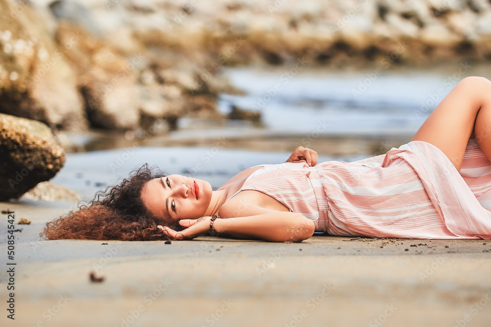 Beautiful young Latin woman enjoying the beach lying on the sand. on the beaches of huatulco, oaxaca, mexico.