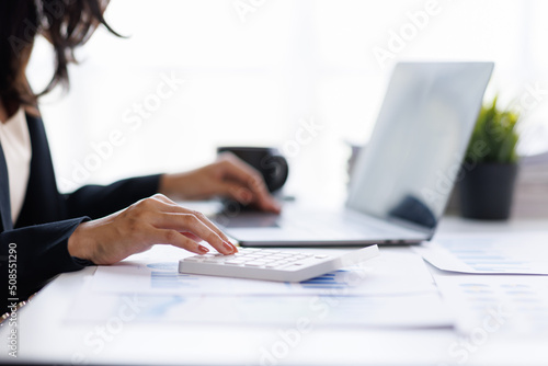 businesswoman Using calculator and tablet working at office with document on her desk, doing planning analyzing the financial report, business plan investment, finance analysis concept. 