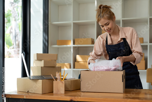 Asian female online store small business owner seller entrepreneur packing package post shipping box preparing delivery parcel on table. Ecommerce dropshipping shipment service concept.