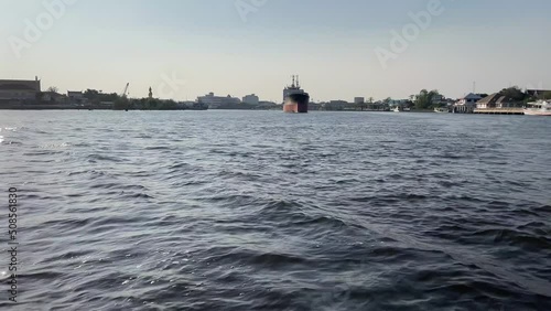 POV riding ferry boat from Thachalom pier to Mahachai pier. Beautiful river with blue sky view. Ship cruise floating on water - day photo