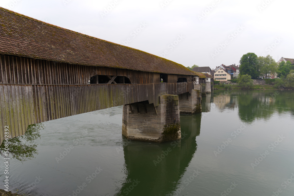 Covered wooden bridge over the Rhine River at Stein, Canton Aargau, and Bad Säckingen, Baden-Württemberg, on a cloudy spring day. Photo taken May 6th, 2022, Stein, Switzerland. Covered wooden bridge over the Rhine River at Stein, Canton Aargau, and Bad Säckingen, Baden-Württemberg, on a cloudy spring day. Photo taken May 6th, 2022, Stein, Switzerland.