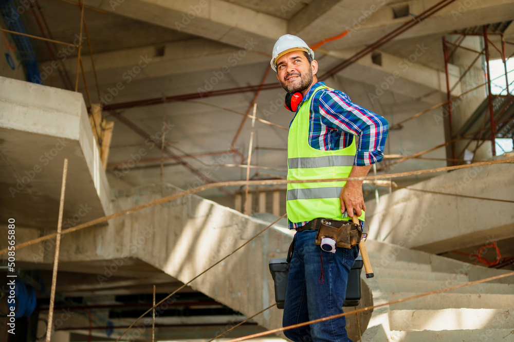 A portrait of a foreman in his 40s who descends the stairs with a tool box on the construction site. A portrait of a foreman in his 40s who descends the stairs with a tool box on the construction site.