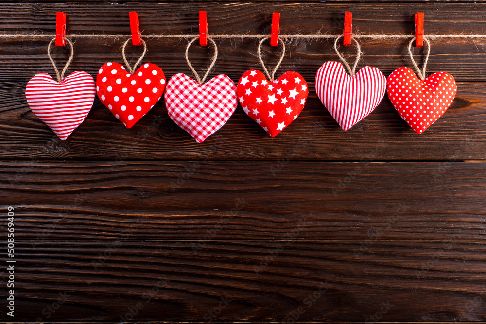 Valentine fabric hearts hanged on rope on dark wooden background