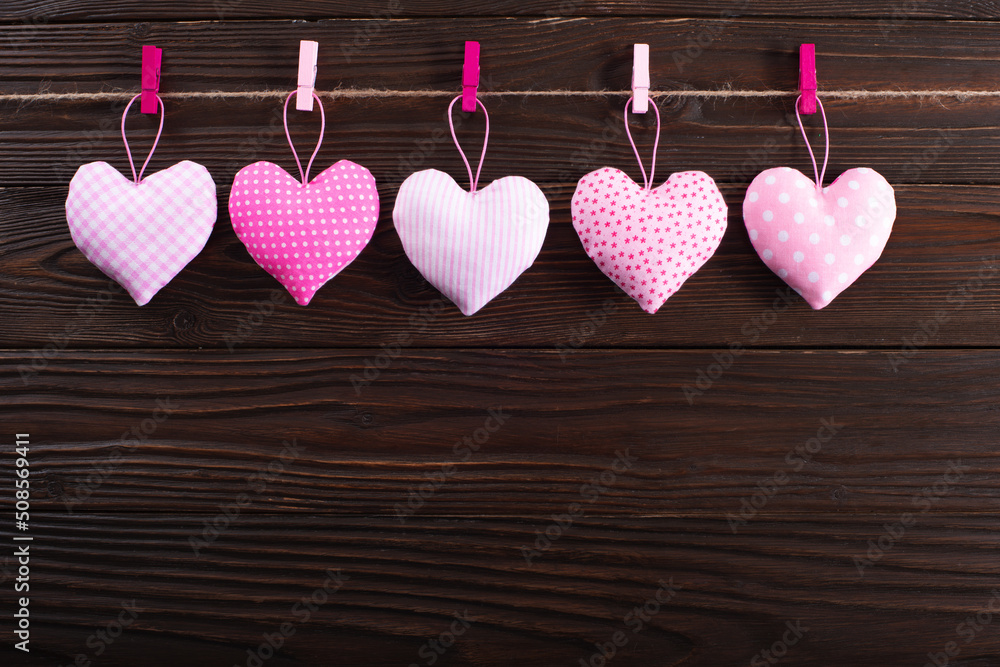 Valentine fabric hearts hanged on rope on dark wooden background
