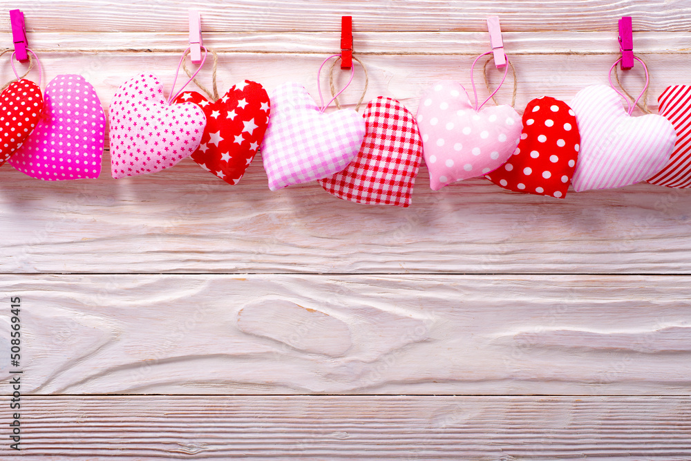 Valentine fabric hearts hanged on rope on white wooden background